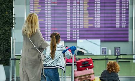 Family checking airport departure board while traveling for Passover