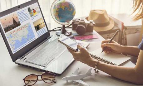 Traveler researching destinations online while planning a trip with laptop, phone, and globe