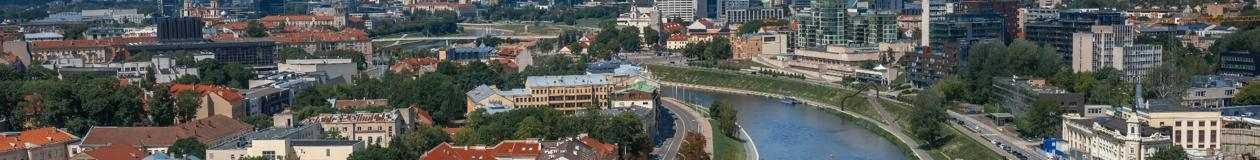 Wide panoramic view of Vilnius Old Town with red rooftops, churches, and green hills, used for the Passover programs in Lithuani
